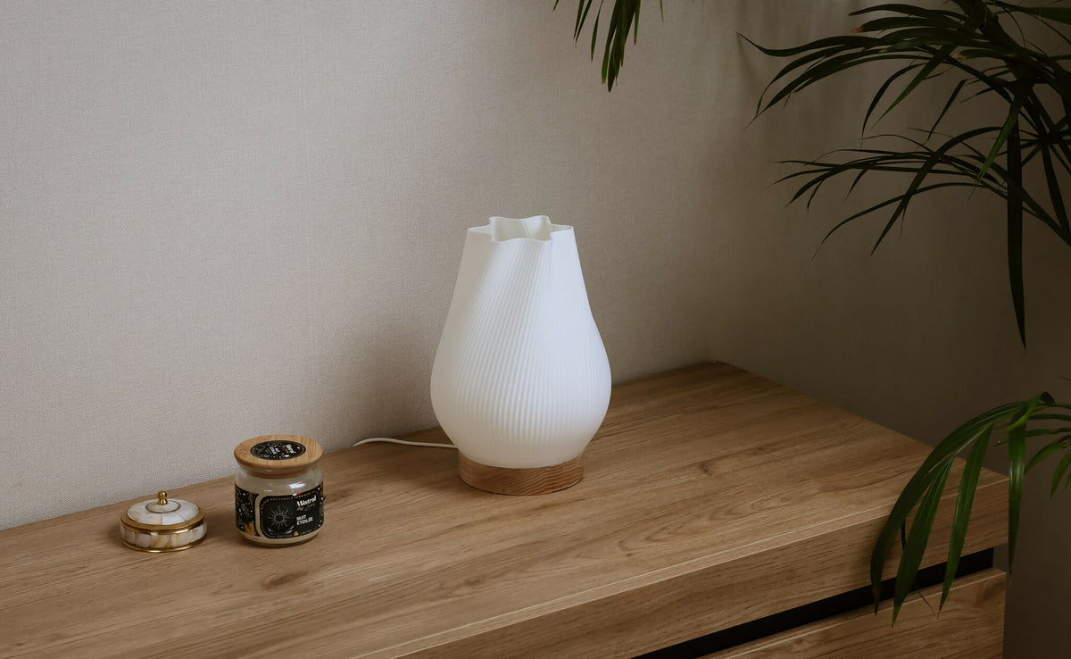 Lampe d’intérieur compacte à abat-jour blanc côtelé et base en bois, près d’objets.