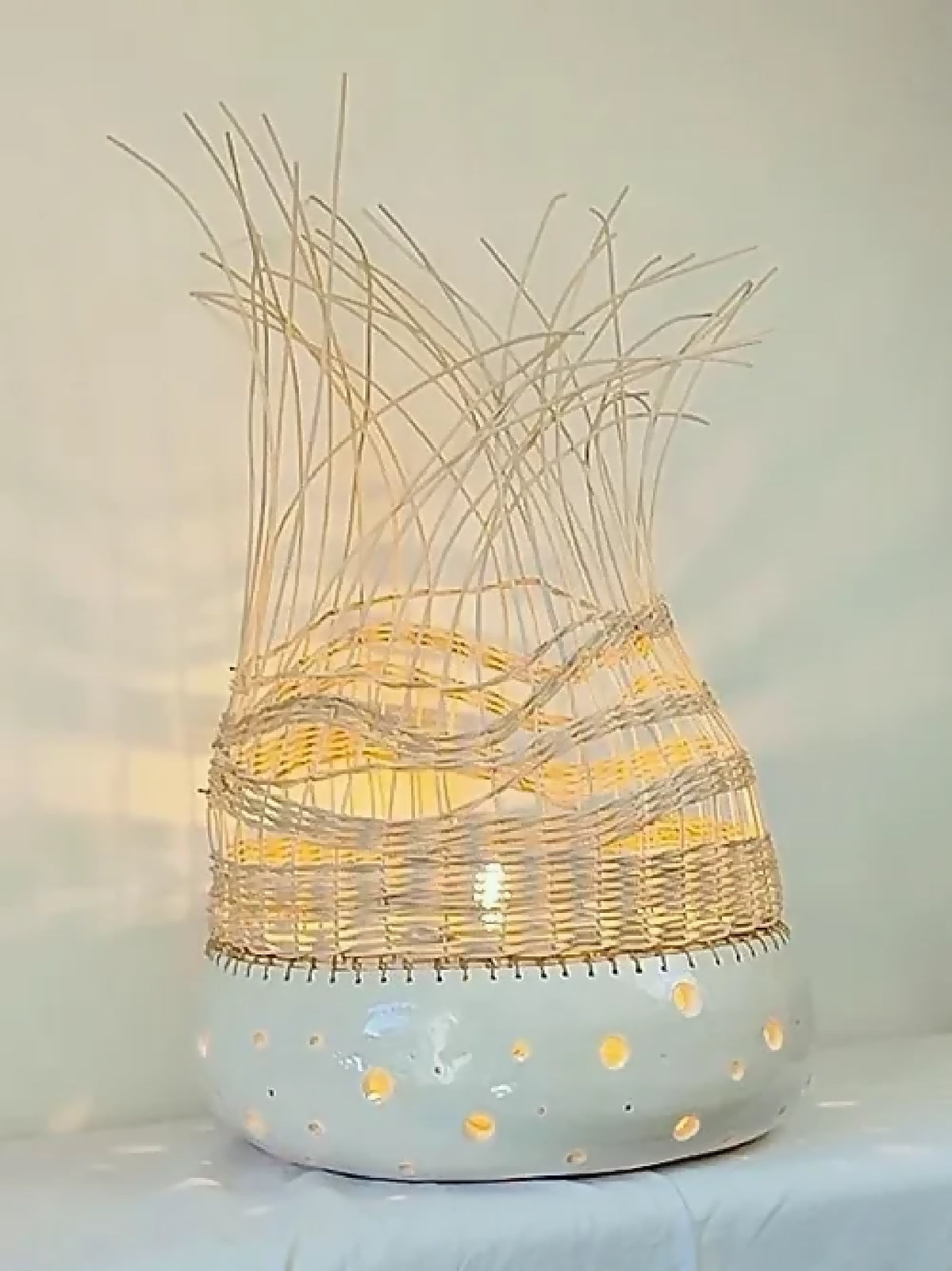 Lampe à poser en tressage clair, base blanche à pois, brins jaunes au-dessus.