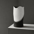 Vase décoratif grand cylindre noir, intérieur clair, posé sur socle