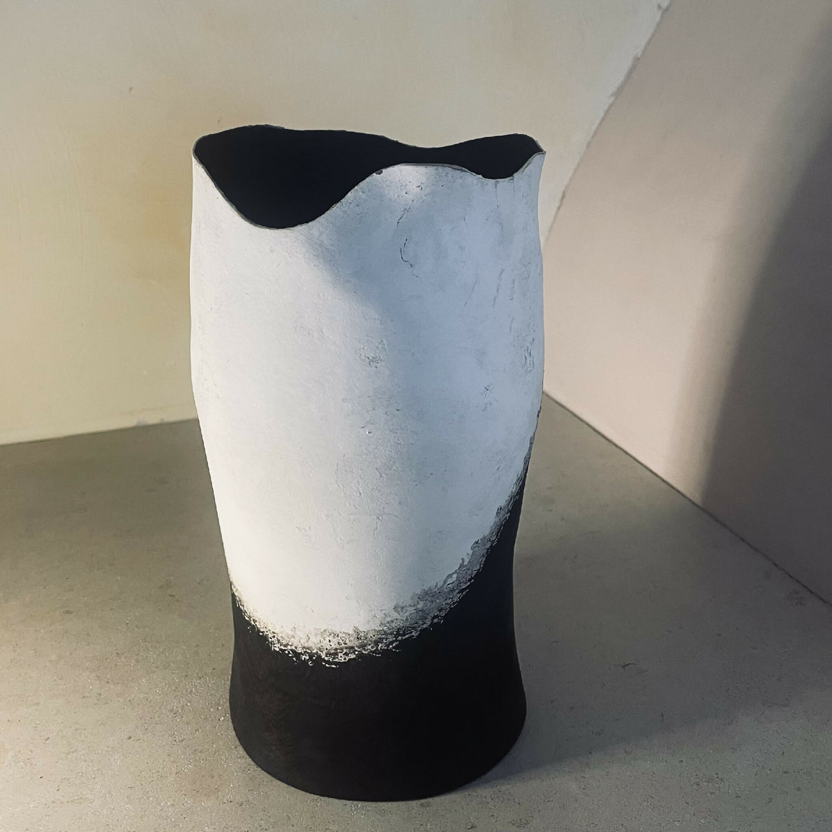 Vase sculptural bicolore noir et clair, forme évasée, surface patinée et irrégulière