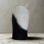 Vase conique noir et blanc, sommet arrondi ouvert, texture mate et patine visible