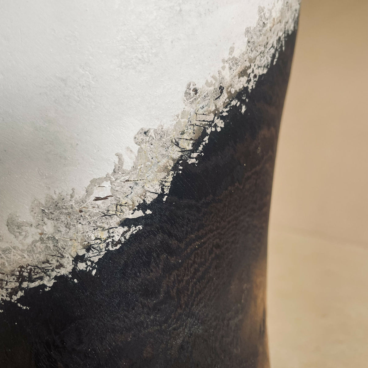 Détail du vase : surface noire et claire avec éclats et lignes de matière, aspect patiné