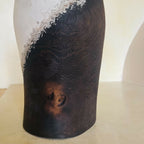 Vase noir et clair, texture en relief avec motif tourbillonnant, traces brunes visibles