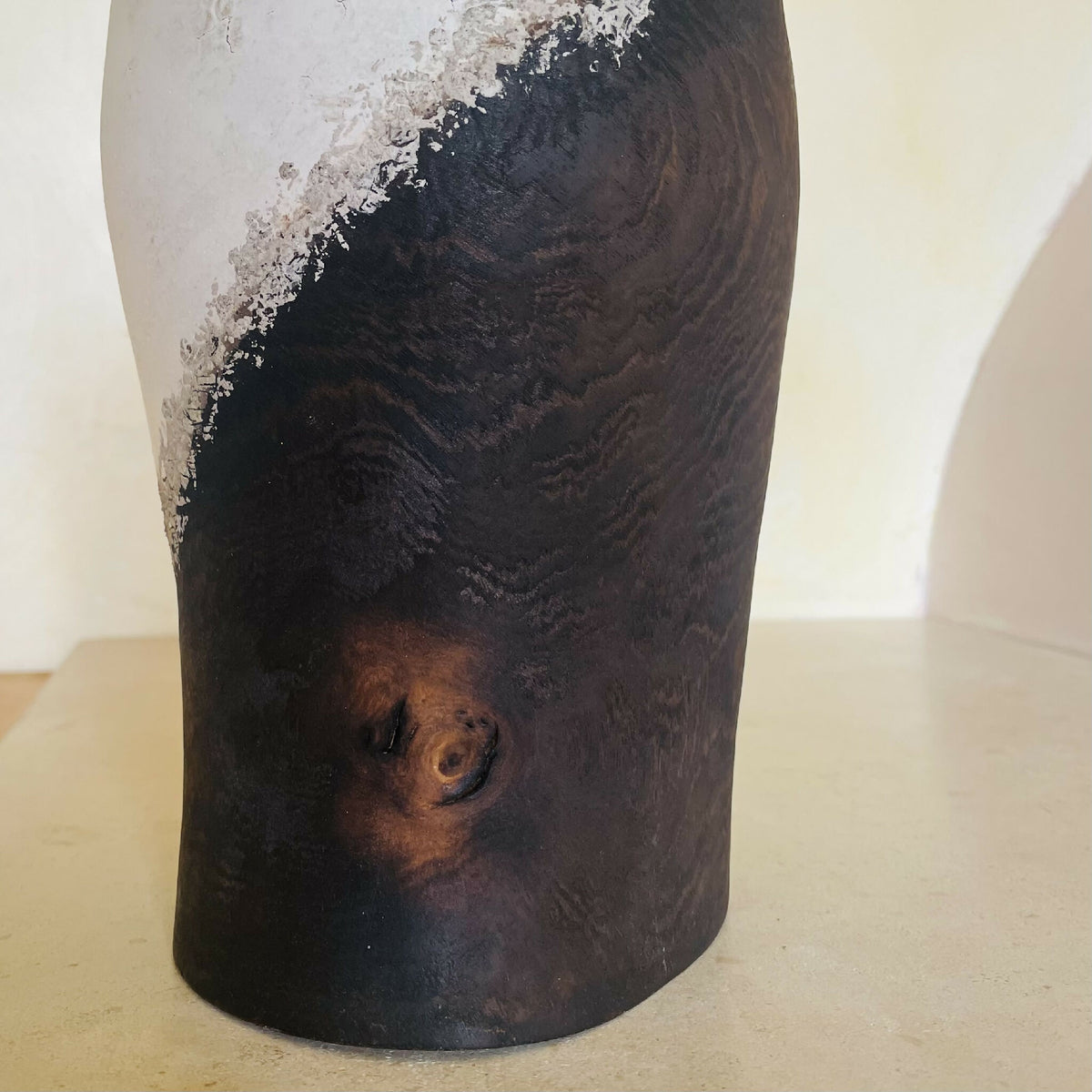 Vase noir et clair, texture en relief avec motif tourbillonnant, traces brunes visibles