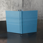 Livre d’or bleu, couverture ouverte en V avec marque-page et pages visibles.