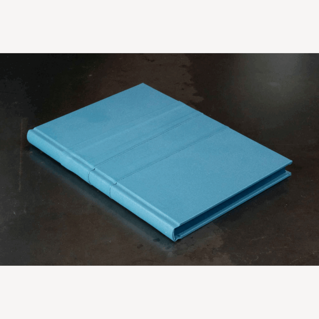 Livre d’or bleu, couverture fermée vue en angle avec tranches visibles.