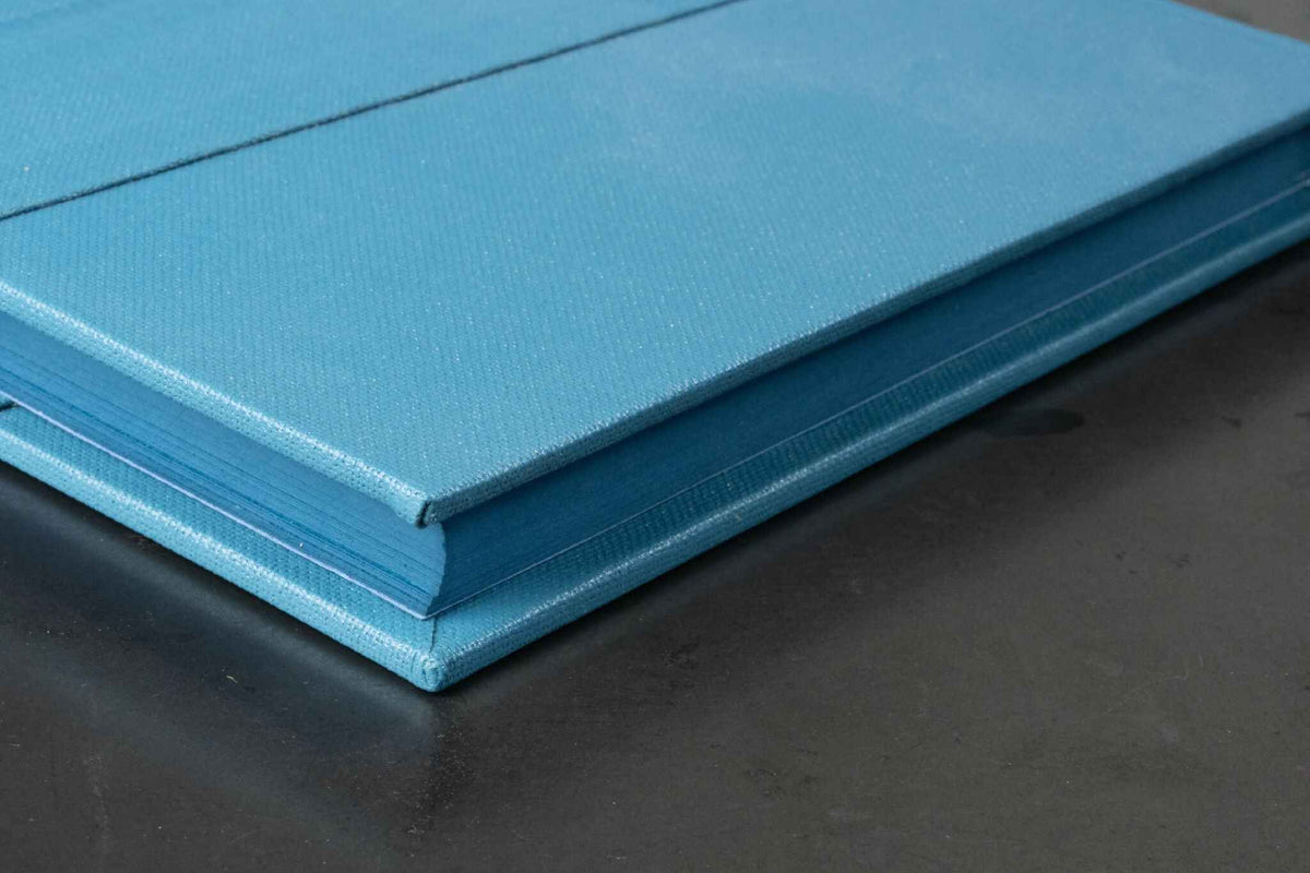 Livre d’or bleu clair en tissu, vue rapprochée du coin et des tranches.