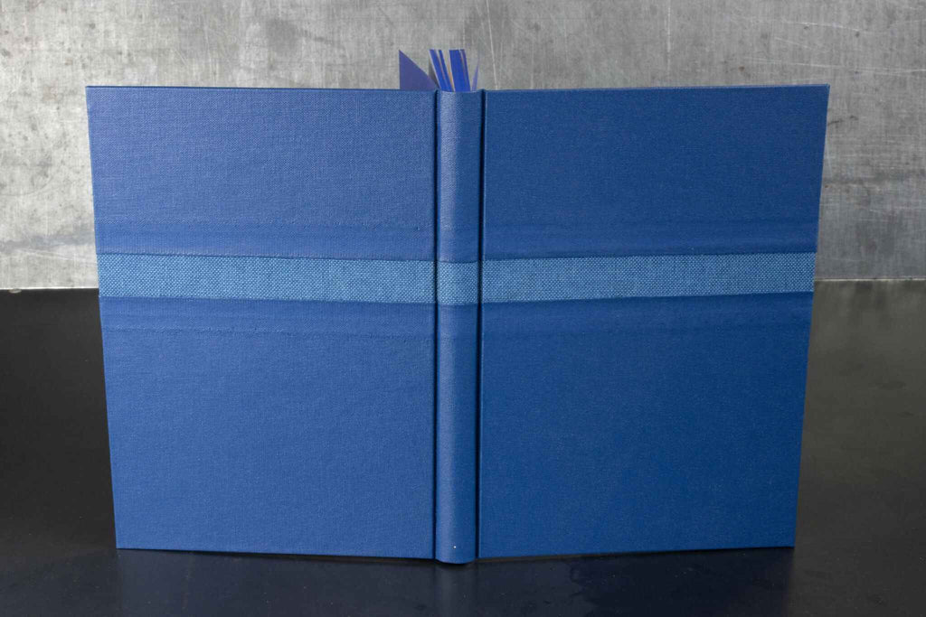 Livre d’or bleu, couverture ouverte avec un ruban de marque-page et des pages.