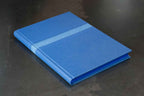 Livre d’or bleu, couverture rigide fermée avec couture décorative sur le dessus.