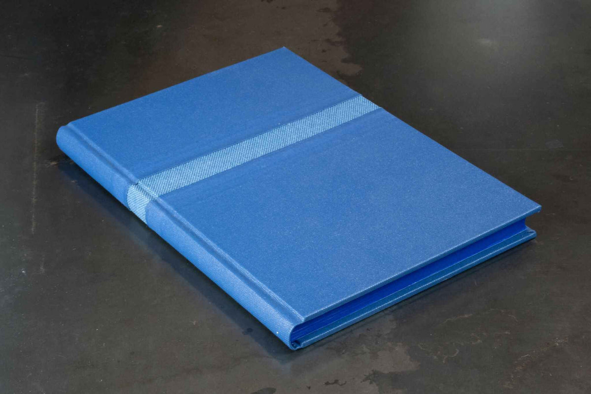 Livre d’or bleu, couverture rigide fermée avec couture décorative sur le dessus.