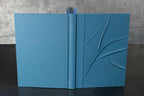Carnet bleu à reliefs, couverture texturée avec motif en relief, pages ouvertes