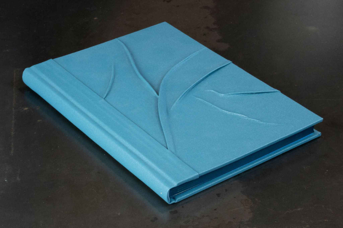 Carnet bleu à reliefs, couverture fermée, motif abstrait en relief