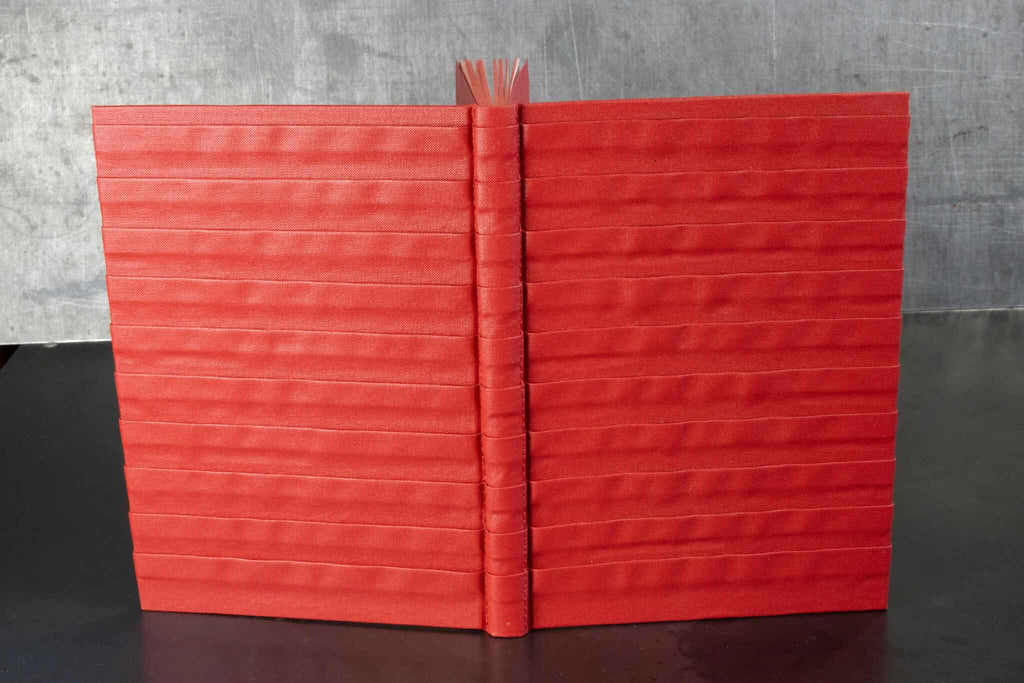 Carnet rouge à reliefs, couverture ouverte avec dos au centre