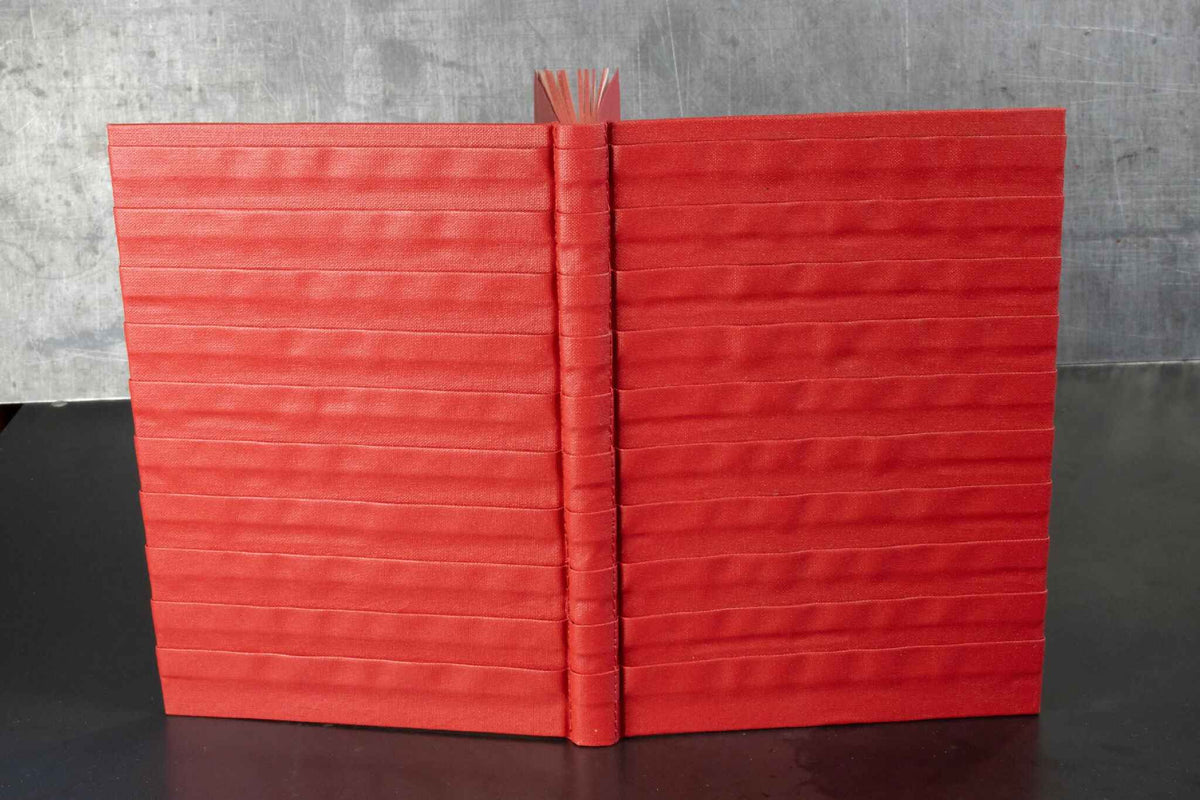 Carnet rouge à reliefs, couverture ouverte avec dos au centre