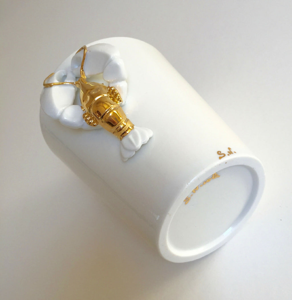 Mug blanc en céramique avec décor homard doré, poignée et bord visibles