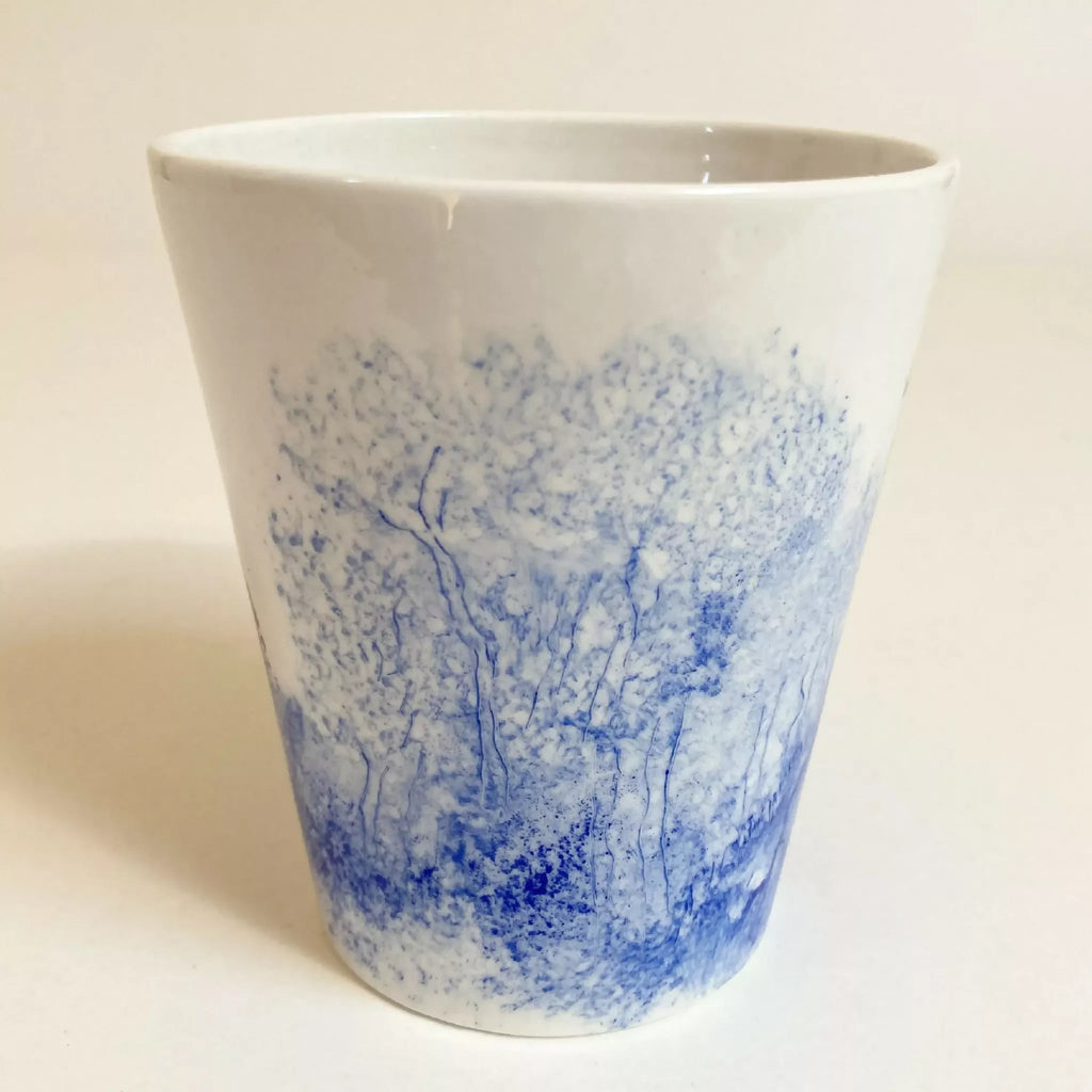 Mug en céramique blanc, vue de face avec paysage bleu et tracés d’arbres