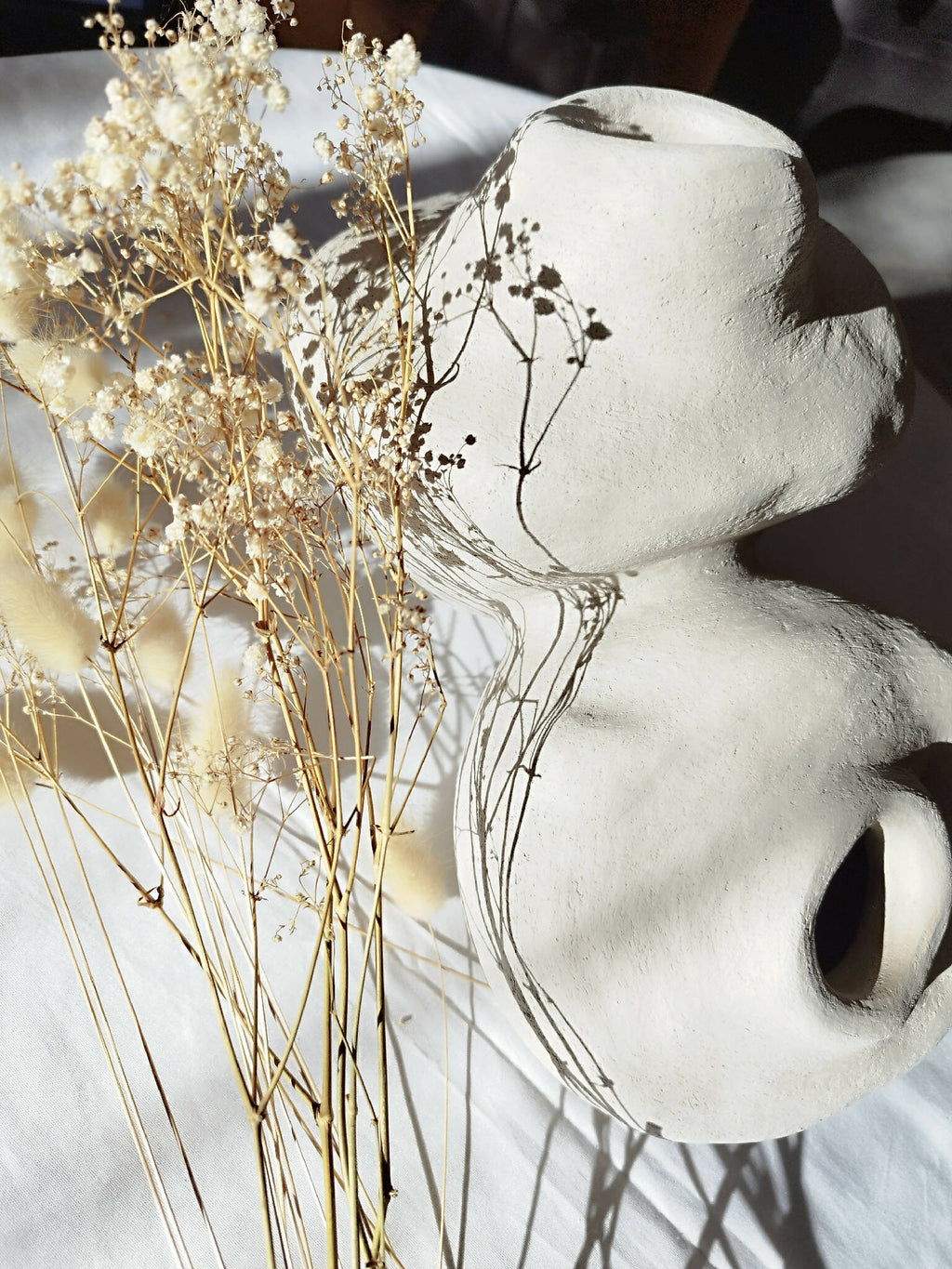 Peluche décorative blanche de profil, grandes oreilles et museau avec ombres, brins dorés au fond.