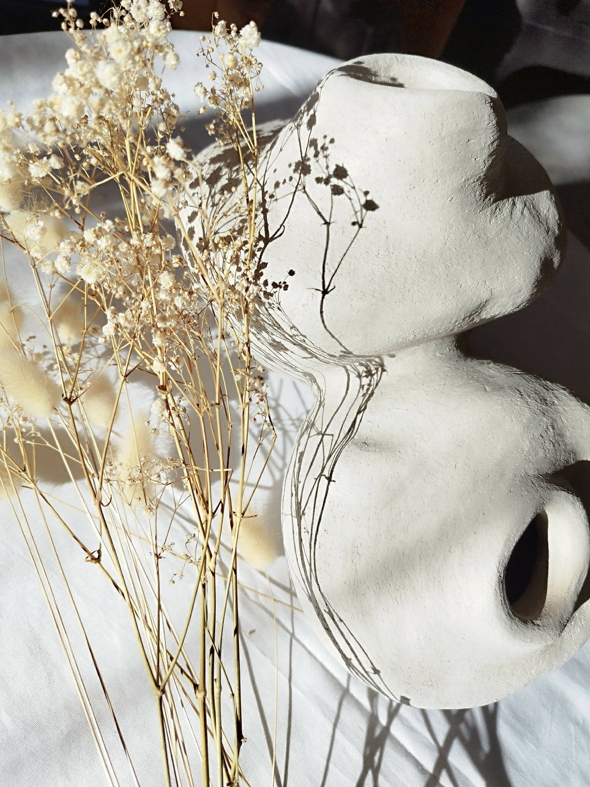 Peluche décorative blanche de profil, grandes oreilles et museau avec ombres, brins dorés au fond.