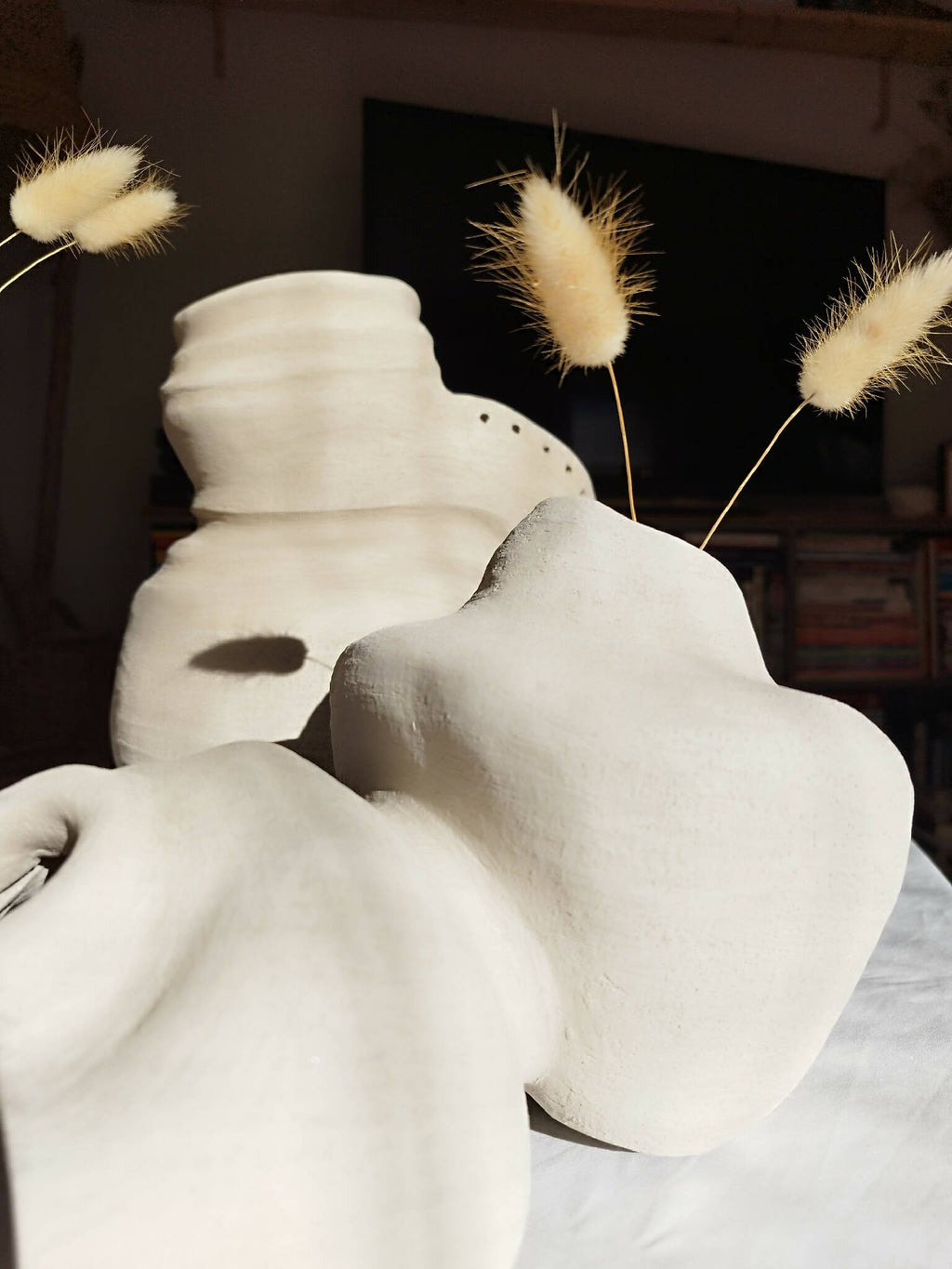 Peluche décorative blanche avec museau sculpté, yeux en amande et touffes beige suspendues.