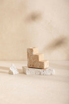 Bougeoir à base en blocs beige sable, socle en pierre claire texturée, sans bougie