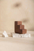 Bougeoir MATTEO en céramique mate brun, forme de blocs, ouverture pour bougie sur socle clair.