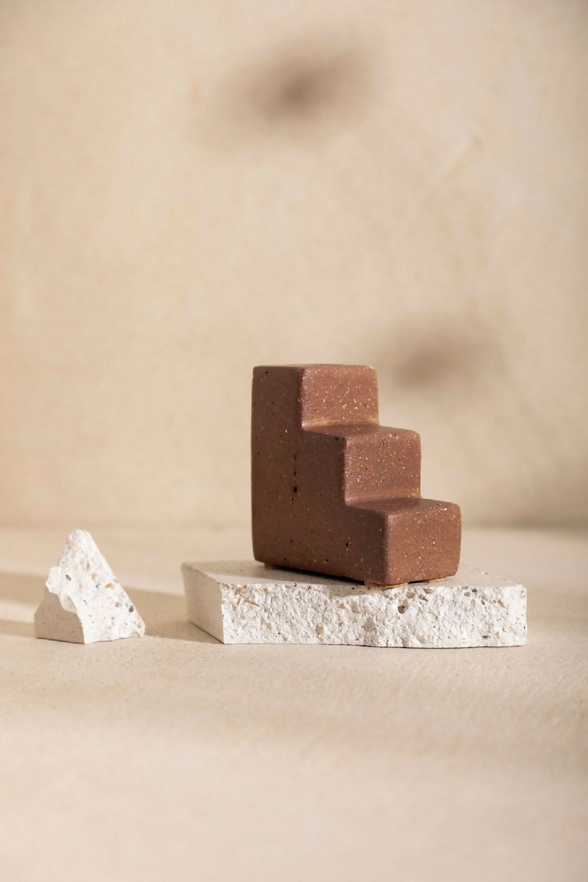 Bougeoir MATTEO en céramique mate brun, forme de blocs, ouverture pour bougie sur socle clair.