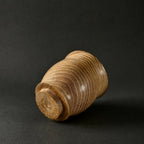 Gobelet en céramique beige, lignes ondulées sur la surface cylindrique.
