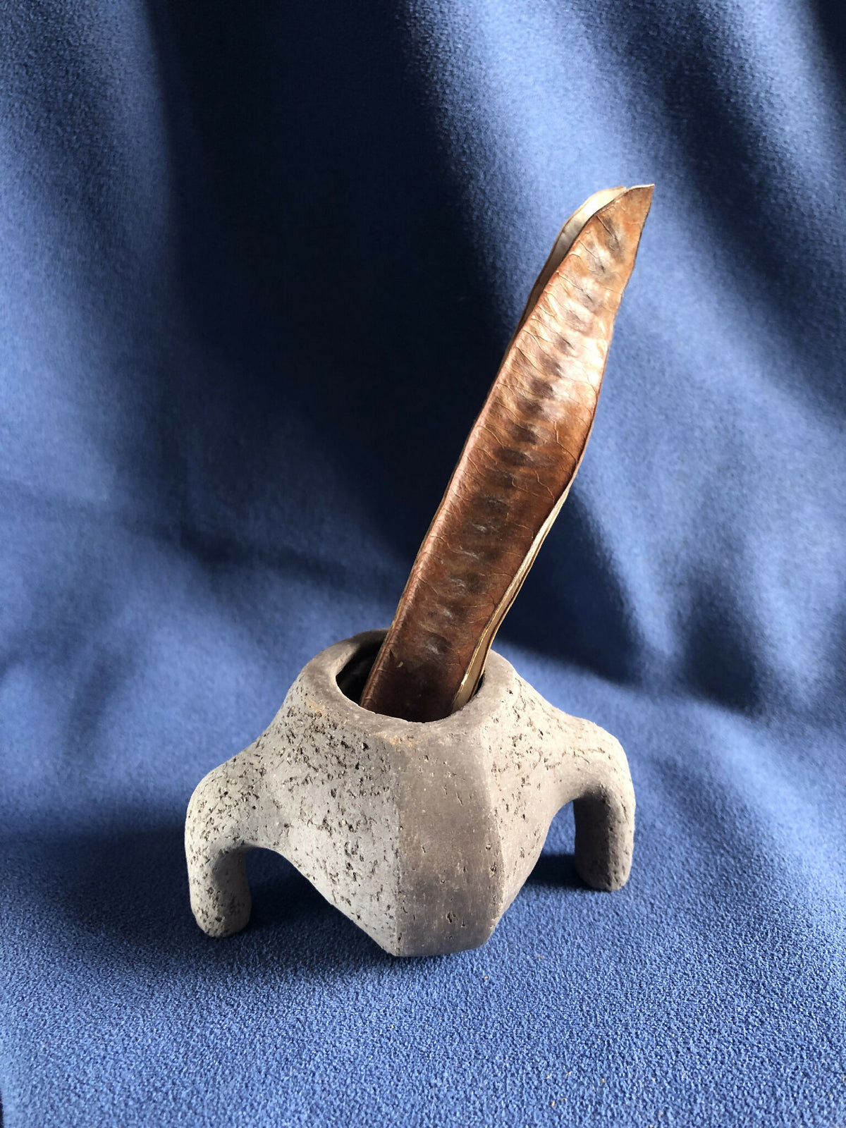 Petit pot en pierre grise avec tige en bois insérée dans l’ouverture.