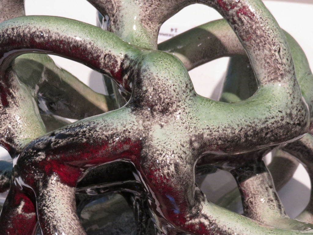 Sculpture Nodulus : gros plan métal vert-gris et rouge, entrelacs de boucles.