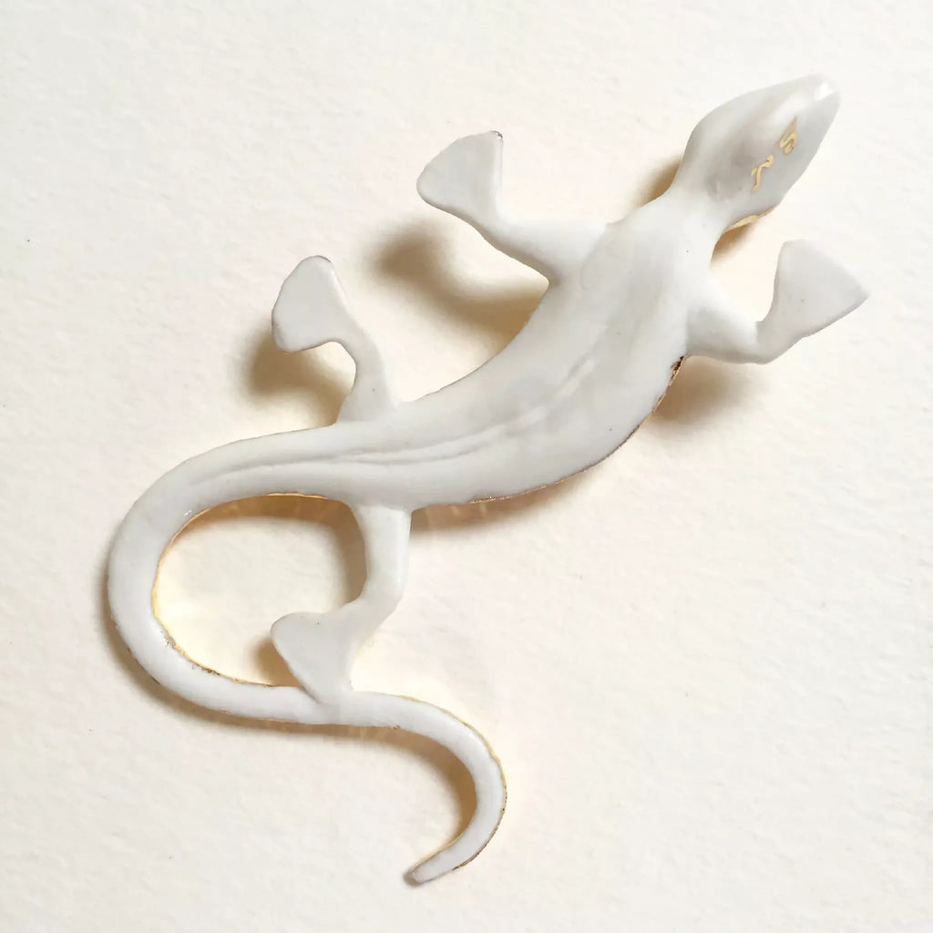 Sculpture de salamandre blanche avec liseré doré, queue enroulée et pattes écartées