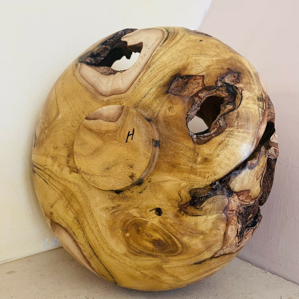 Sculpture en bois contre surface claire, cavités noires et veines miel au relief marqué