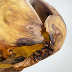 Gros plan sculpture en bois, veines ondulées miel et brun, texture piquée et sombre