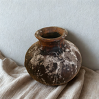 Vase en terre cuite brun foncé, col évasé, taches blanchâtres et texture usée.