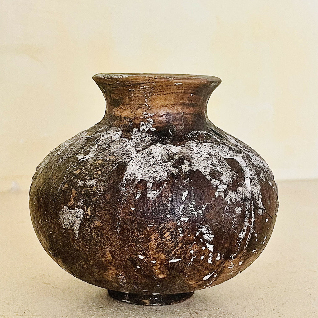 Vase en poterie brun foncé, vue de face, col évasé, usure avec taches blanchâtres.