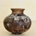 Vase en poterie brun foncé, vue de face, col évasé, usure avec taches blanchâtres.