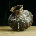 Vase en terre cuite brun, col évasé, aspect ancien avec dépôts blanchâtres.