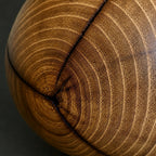 Détail vase en bois : lignes concentriques du grain, teintes miel et brunes.