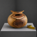 Vase en bois sculpté avec grande ouverture circulaire, rainures du grain visibles.