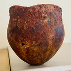 Vase en métal oxydé, teintes brun rouge et mauve, forme arrondie, fond visible.