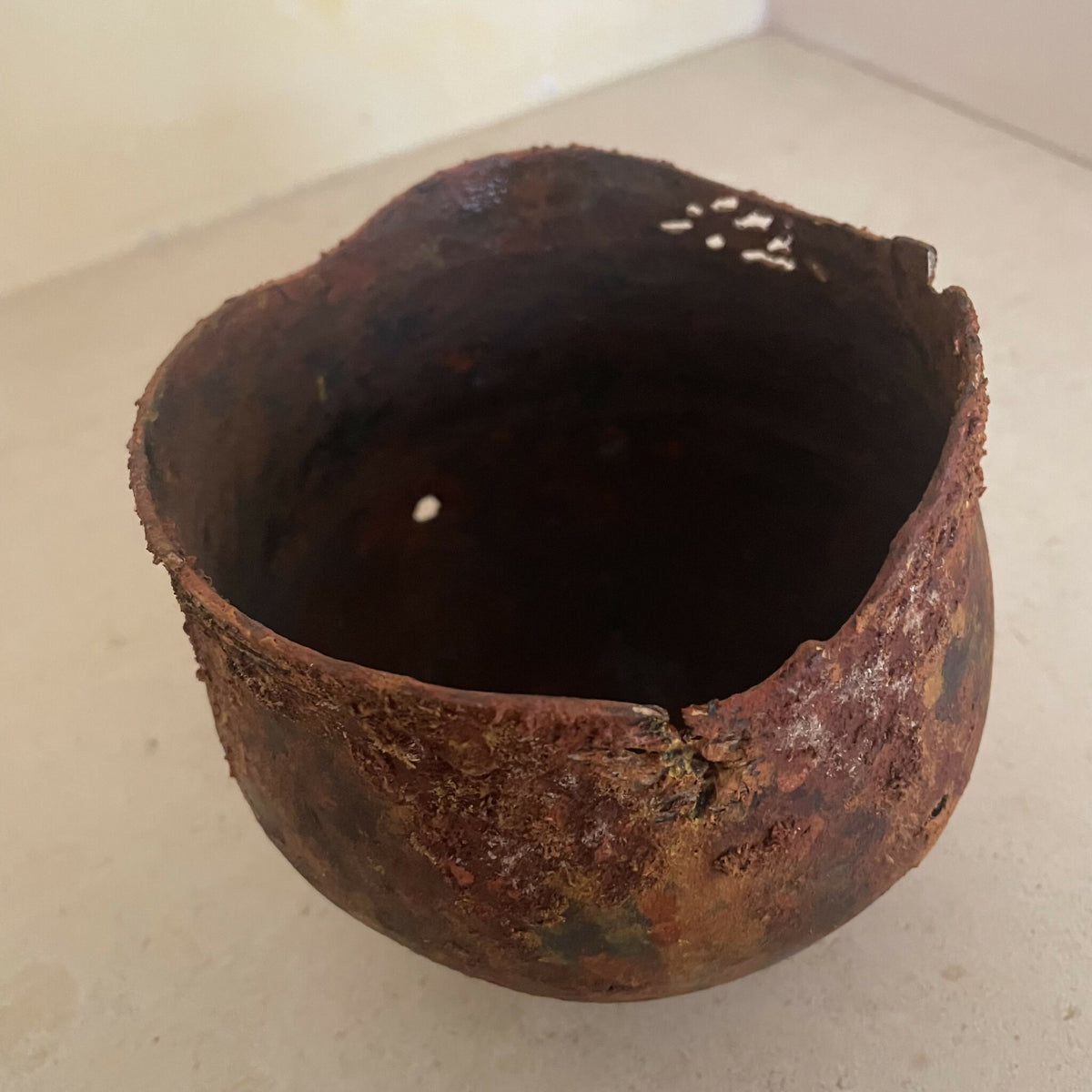 Coupe en métal oxydé brun rouille, bords irréguliers, intérieur foncé