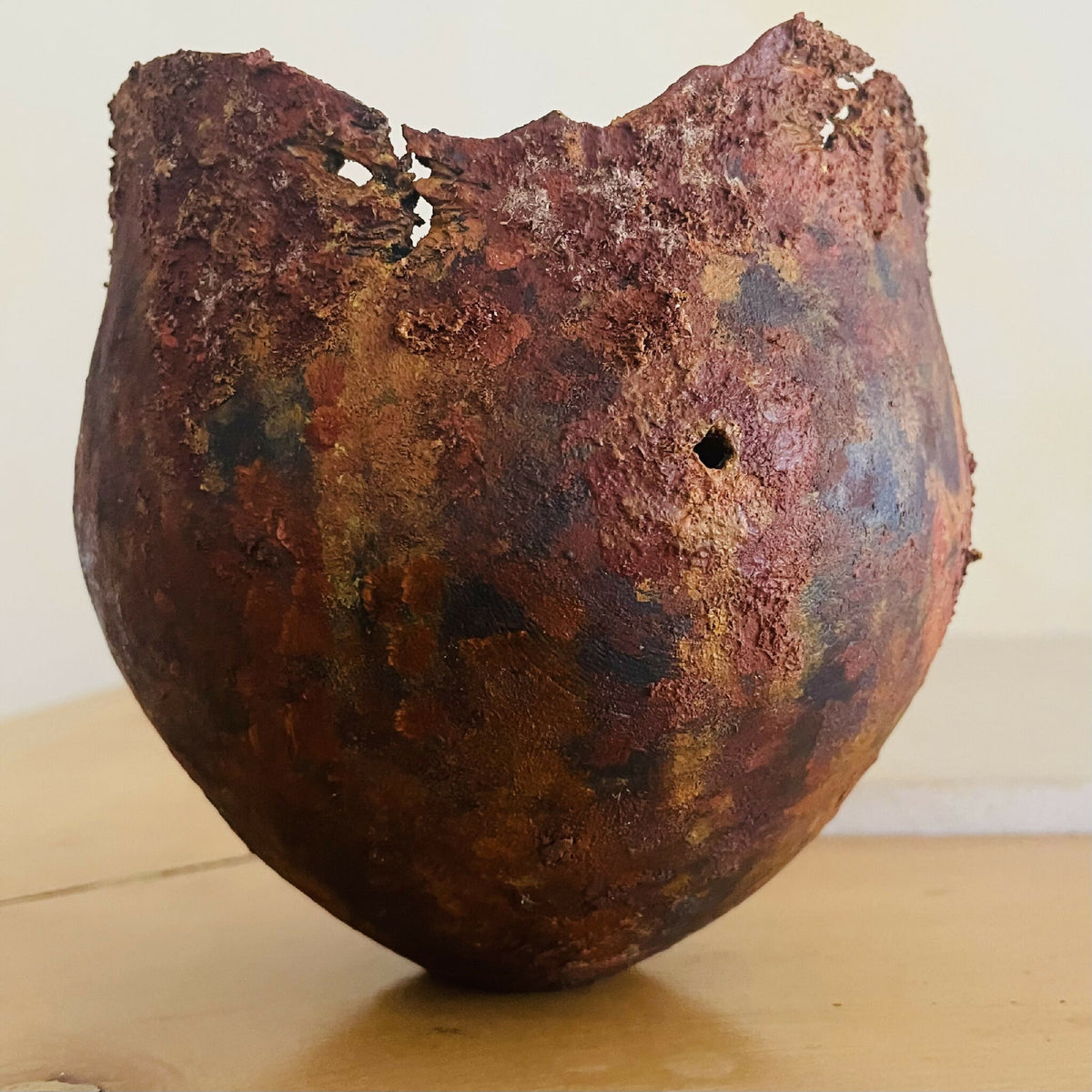 Vase en métal oxydé brun rouge et mauve, éclats sur le bord, petit trou apparent.