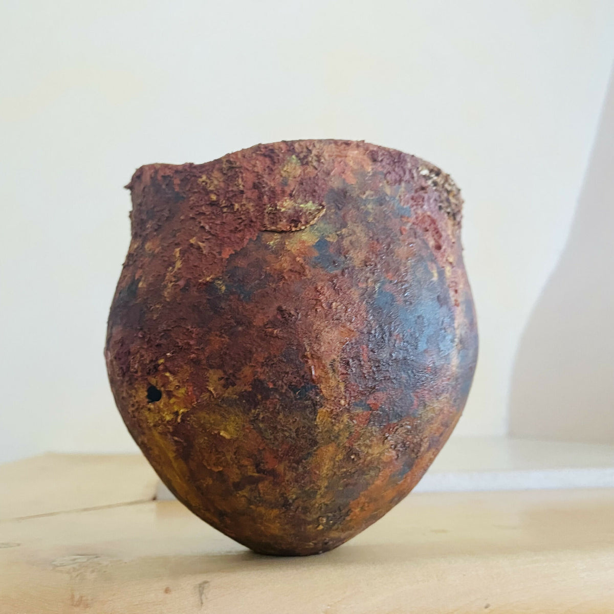 Vase en métal oxydé brun rouge, bord irrégulier, aspect patiné avec zones bleu/gris.