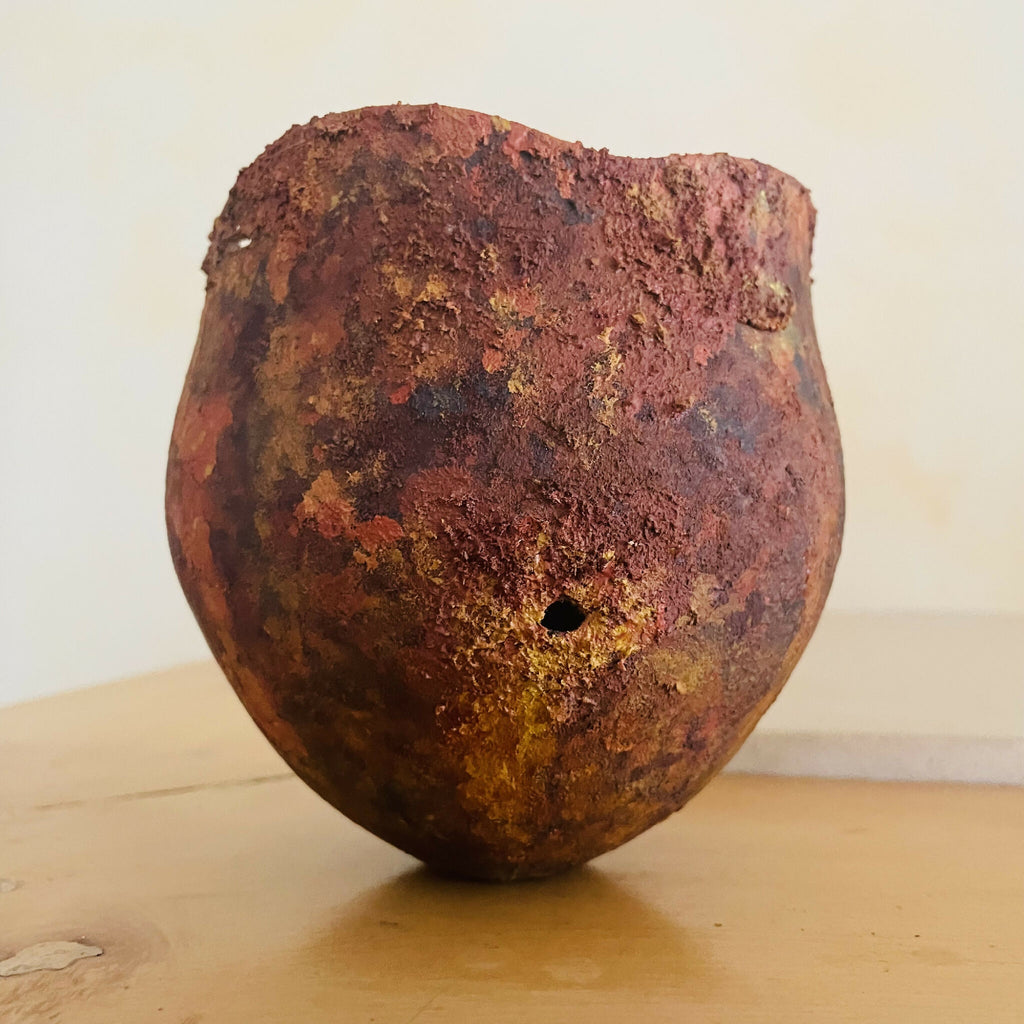 Vase en métal oxydé brun rouge, surface texturée, petit trou sur le côté.