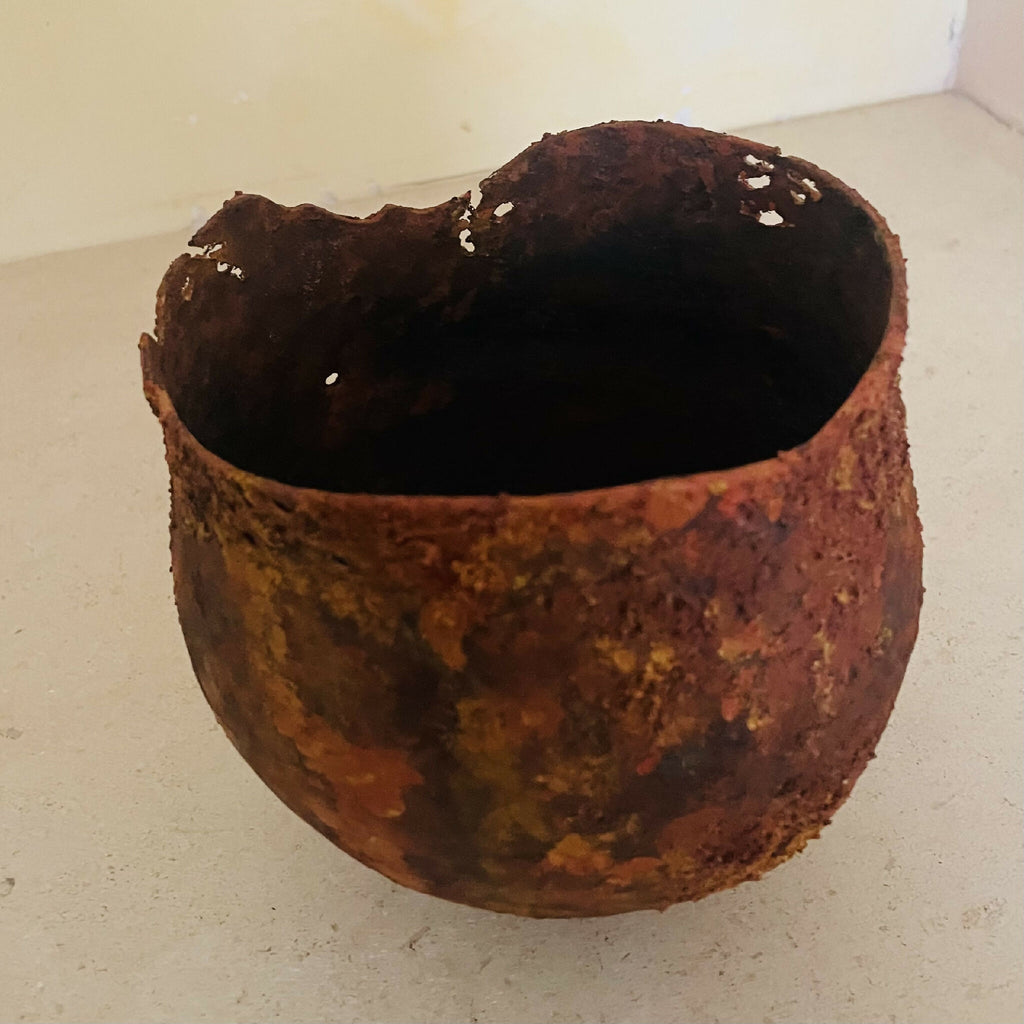 Vase en métal oxydé, vue de dessus avec intérieur sombre, bord ébréché.