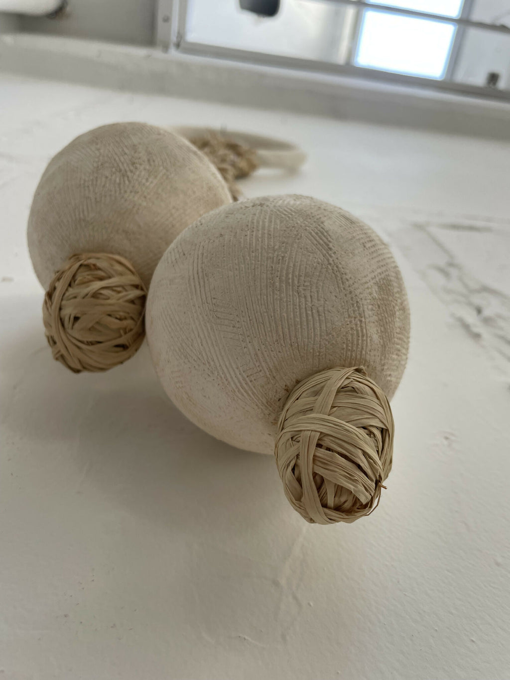 Décoration murale avec deux boules en tissu beige et nœuds en corde