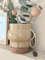 Vase céramique beige à anse, fond brun, tige décorative avec feuilles et petites boules sèches
