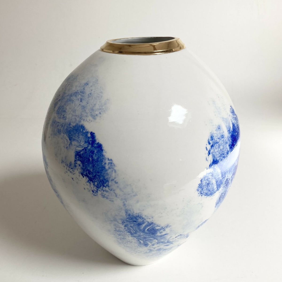 Vase blanc avec décor bleu sur fond clair et col doré