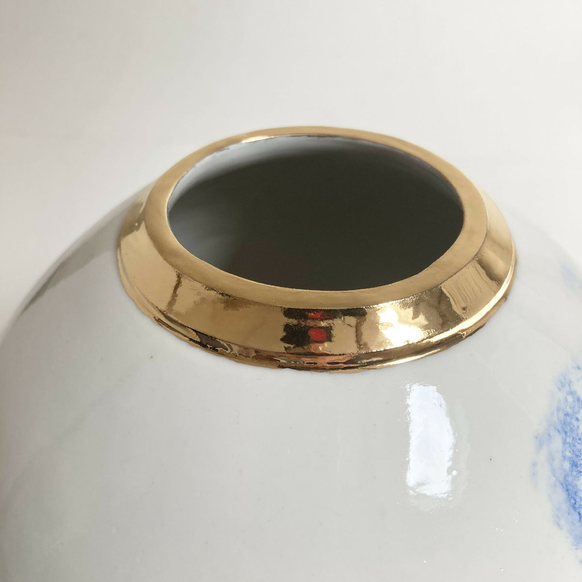 Vase blanc à col doré, intérieur noir, décor bleu partiel visible