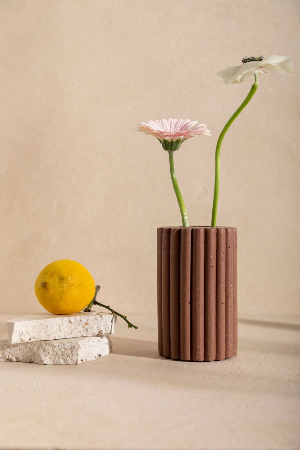 Vase en céramique brune striée, avec ouverture et fleurs rose et violettes.