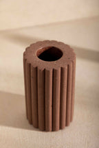 Vase en céramique brune striée, vue du dessus avec ouverture sombre.